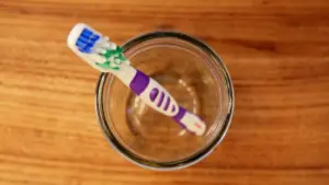 Spazzolino da denti in un bicchiere visto dall'alto su fondo in legno