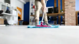 Persona che lava il pavimento con un mocio in un ambiente domestico o ufficio