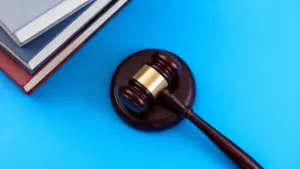 Martelletto da giudice con alcuni libri su sfondo blu