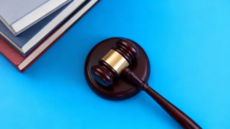 Martelletto da giudice con alcuni libri su sfondo blu