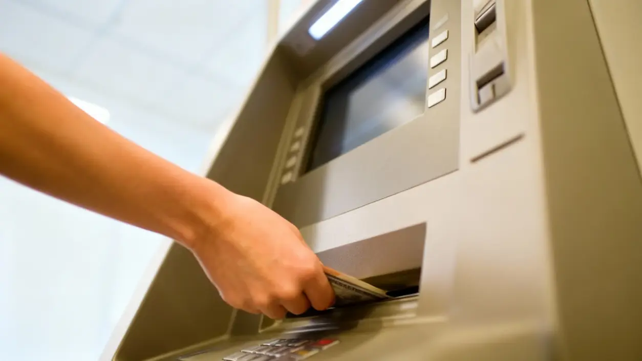 Persona che preleva contanti da uno sportello bancomat