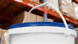 Secchio bianco con coperchio blu in un magazzino con scaffali e scatole