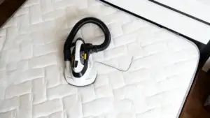 Aspirapolvere su un materasso chiaro per rimuovere polvere e acari