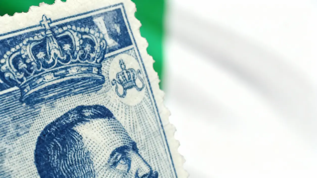 Dettaglio di un vecchio francobollo blu con corona e ritratto maschile su sfondo tricolore