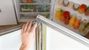 Mano che pulisce la guarnizione del frigorifero per rimuovere condensa e sporco