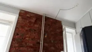 Parete in mattoni a vista con tubature e arredamento minimal in un piccolo appartamento